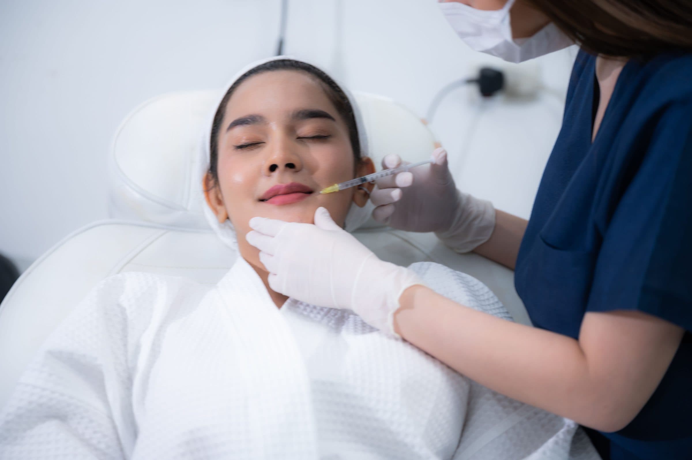 Provider in gloves treating a reclined patient's face