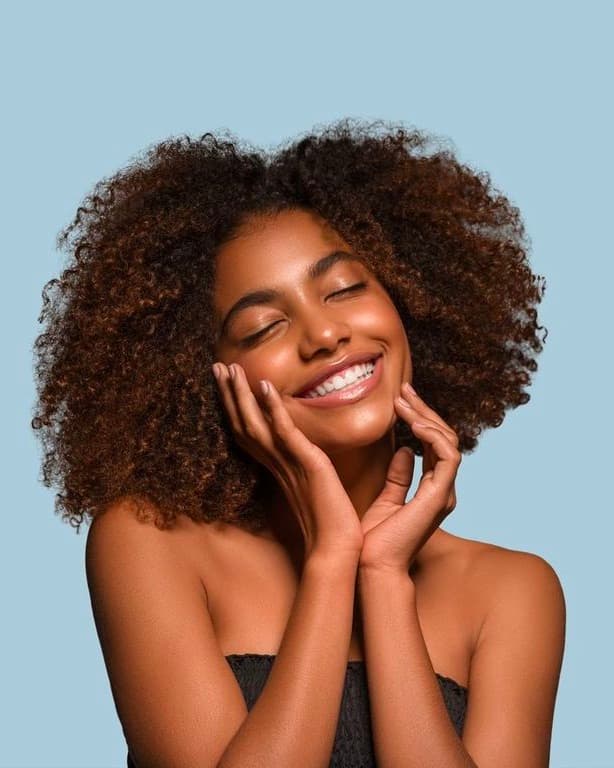 A smiling woman with her hands cupped against her cheeks