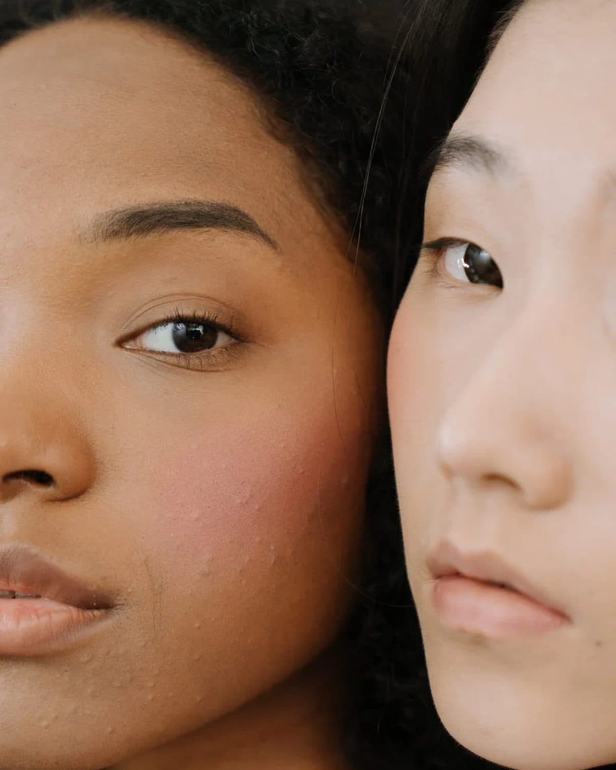 Close crop of two women’s faces showing bare, natural skin texture